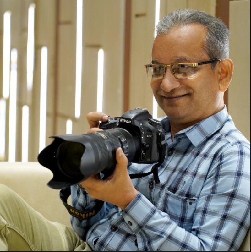 A photographer from Shankar Photo Vision holding a Nikon DSLR with a fast zoom lens